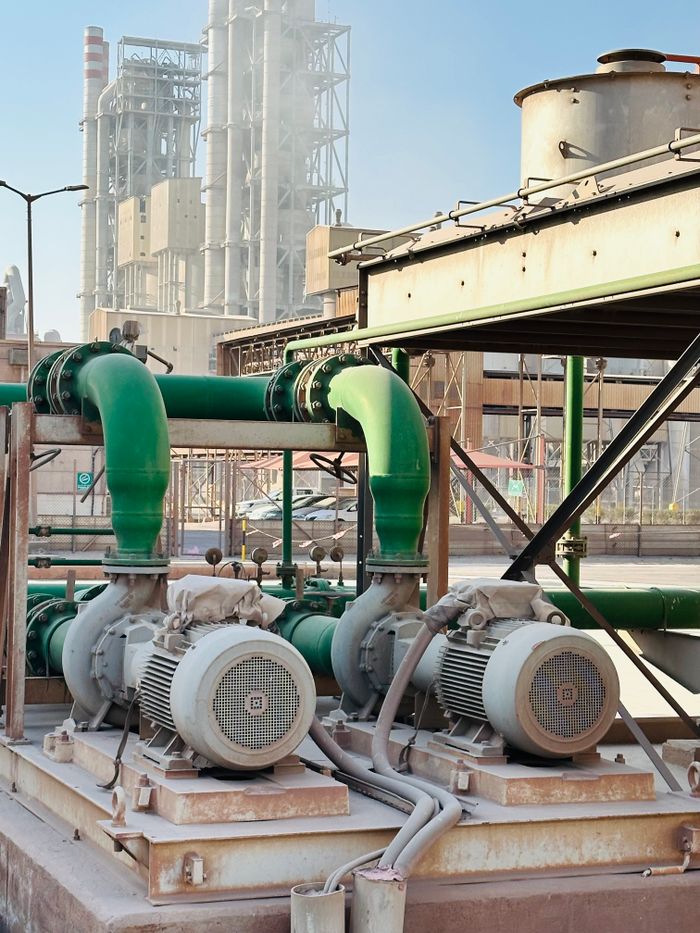 Services Outdoor scene of industrial machinery with distinct green pipes at a large factory.